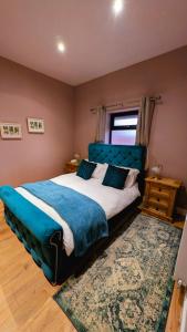 a bedroom with a large bed with a blue headboard at Beech Tree Park Cottages in Hatfield