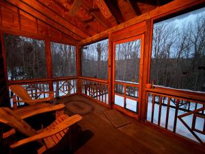a cabin with a rocking chair on a porch with windows at Adirondack Butterfly Hillside in North Creek