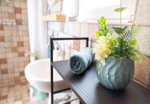a vase with flowers on a table in a bathroom at Ezüstfenyő vendégház in Balatonalmádi +32 photos