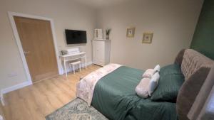 a bedroom with a bed and a couch and a television at Beech Tree Park Cottages in Hatfield