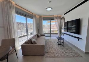a living room with a couch and a large window at נווה ים סוף - מתחם דירות נופש פרימיום באילת in Eilat