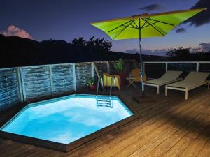 a swimming pool with an umbrella on a deck at Bungalow Villa-Déhé in Deshaies +16 photos