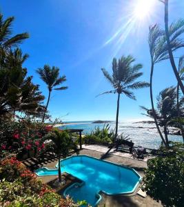 a swimming pool next to the beach with palm trees at Pousada Recanto dos Colibris in Guarapari