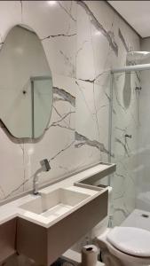 a bathroom with a sink and a mirror and a toilet at Pousada Bella in Vitória da Conquista
