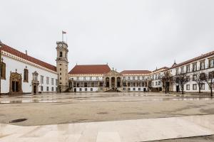 a large building with a clock tower in the middle at HI Coimbra - Pousada de Juventude in Coimbra +28 photos