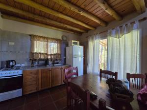 a kitchen with a table and a white refrigerator at Cabaña La Joaquina in Colón