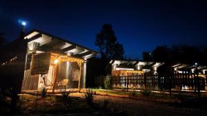 a house lit up at night with lights at Tiny House Detrás del río in Colbún