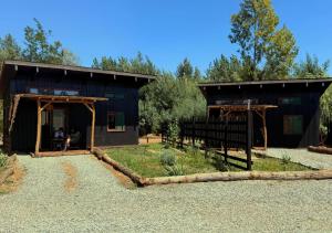 a black barn with people sitting in the doorway at Tiny House Detrás del río in Colbún