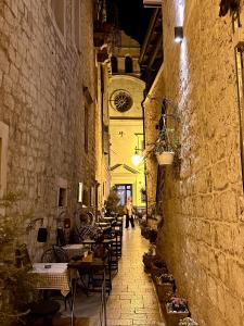 a woman walking down an alley with tables and chairs at Casa Blu in Šibenik