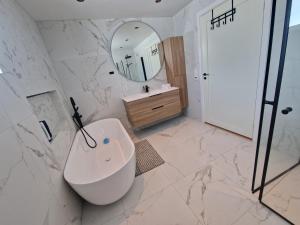 a bathroom with a tub and a sink and a mirror at Villa Modum in Skreppen