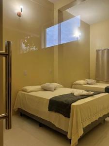 two beds in a room with a large window at Lar dos Lençóis BHS in Barreirinhas