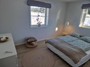 a bedroom with a bed and a table and two windows at Villa Modum in Skreppen