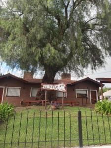 a house with a tree in front of a fence at El Aguaribay de los Nonos in Mina Clavero