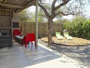 a patio with red and green chairs and a tree at BushGlam Luxury Holiday Home in Hoedspruit