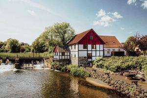 a building with a red roof next to a river at The Mill House - Saeby Watermill in Sæby
