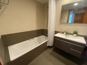 a bathroom with a tub and a sink and a mirror at Osaka Suite in Lloret de Mar