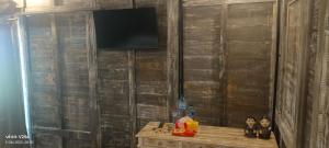 a room with a wooden table with a television on a wall at Resort Gianyar singapadu in Darmasaba