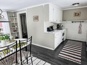 a kitchen with white cabinets and a table in a room at Villa Äppelgården by Interhome in Örebro