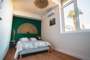 a bedroom with a bed with a green wall at L Escale Balinaise et Spa #7 in Agen +10 photos