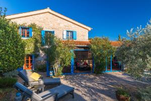 a stone house with blue windows and a yard at Old Stonehouse Stari San in Pinezici
