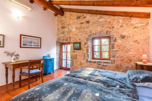 a bedroom with a stone wall and a bed and a desk at Old Stonehouse Stari San in Pinezici
