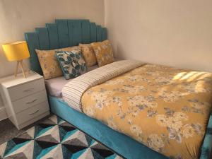 a bed with a blue headboard in a bedroom at Glams one bedroom apartment in Wolverhampton