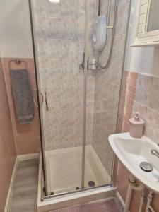 a shower with a glass door next to a sink at Glams one bedroom apartment in Wolverhampton