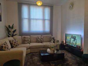 a living room with a couch and a tv at Glams one bedroom apartment in Wolverhampton