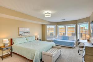 a bedroom with a bed and a chair and windows at 'Phoenix Nest' South Haven Condo: River View! in South Haven