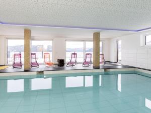 a swimming pool with red chairs in a room at Lärchenhof Top 01 in Mauterndorf