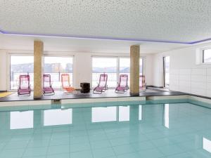 a swimming pool with red chairs in a room at Lärchenhof Top 101 in Mauterndorf