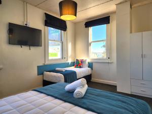 a bedroom with two beds and a flat screen tv at Urban Lounge Sleepery Carterton in Carterton