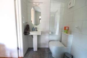a white bathroom with a toilet and a sink at The Lotus Cottage Maleny in Witta +25 photos