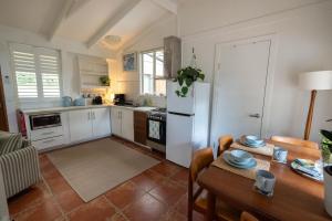 a kitchen with a table and a white refrigerator at The Lotus Cottage Maleny in Witta