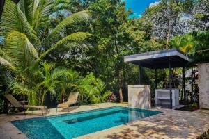 a swimming pool with a umbrella and chairs and trees at Casa escondida in Uvita +17 photos