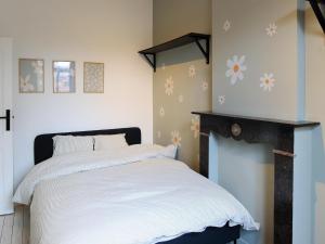 a bedroom with a bed with white sheets and flowers on the wall at Cosy Courtyard House Hasselt in Hasselt