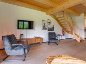 a living room with a staircase and two chairs at Sauna Chalet 9B in Obermöschach