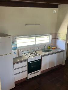 a small kitchen with a stove and a sink at La Calma Casa Quinta in Tandil