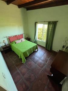 a bedroom with a green bed and a window at La Calma Casa Quinta in Tandil