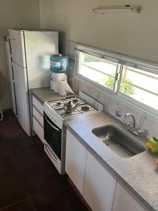 a kitchen with a sink and a stove and a refrigerator at La Calma Casa Quinta in Tandil +3 photos