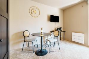 a room with a table and chairs and a tv at Confort et élégance proche centre in Schiltigheim