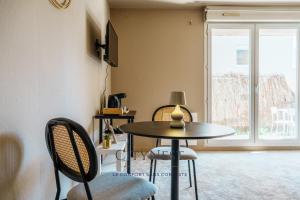 a table and chairs in a room with a window at Confort et élégance proche centre in Schiltigheim