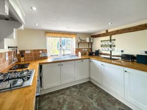 a kitchen with white cabinets and a sink at Poona Cottage in Cadnam +20 photos