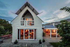 a white house with a patio and a table at Stone Street Cottage by Sothebys Luxury Rental Homes in Wanaka