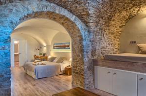 a bedroom with two beds and a stone wall at El Petit Convent in Begur