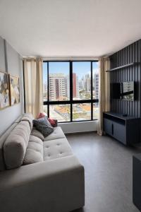 a living room with a couch and a large window at Flat PREMIUM em Manaíra - Sun Beach in João Pessoa