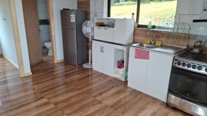 a kitchen with white appliances and a wooden floor at Cabaña7 in Neltume