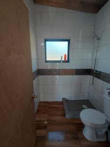 a bathroom with a toilet and a window at Cabaña7 in Neltume