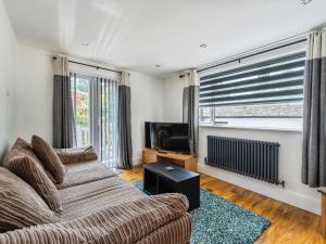 a living room with a couch and a television at Mylnebeck Lodge in Windermere