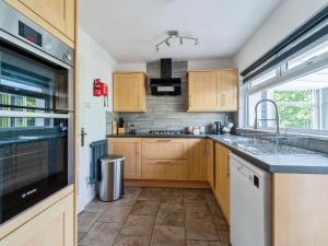 a kitchen with wooden cabinets and a stove top oven at Mylnebeck Lodge in Windermere